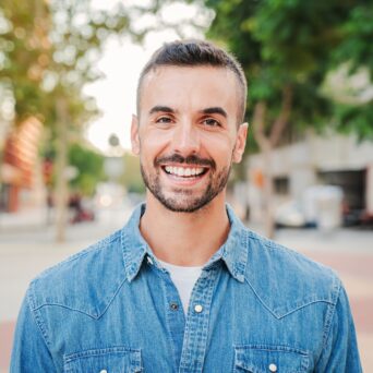 Close up portrait of handsome guy with perfect white teeth smiling and looking at camera standing